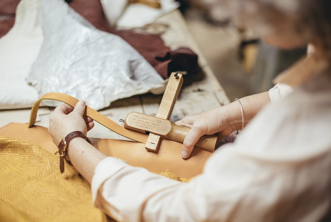 Fotografía profesional de una artesana creando un bolso de cuero