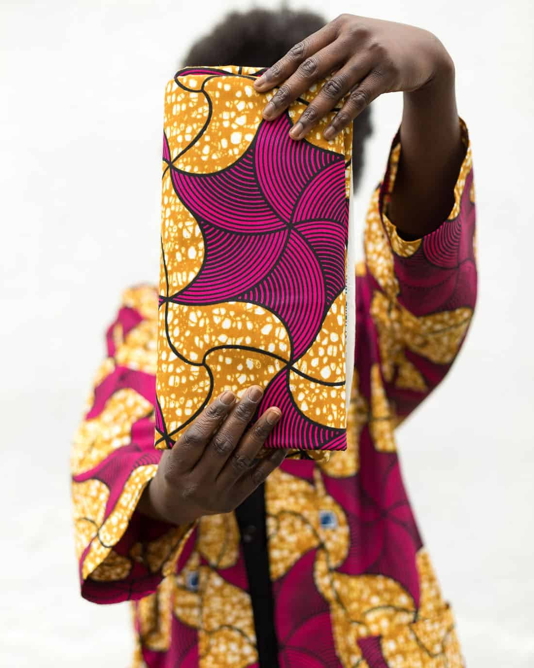 Modelo profesional sujetando unas telas con estampado africano rosas y amarillas