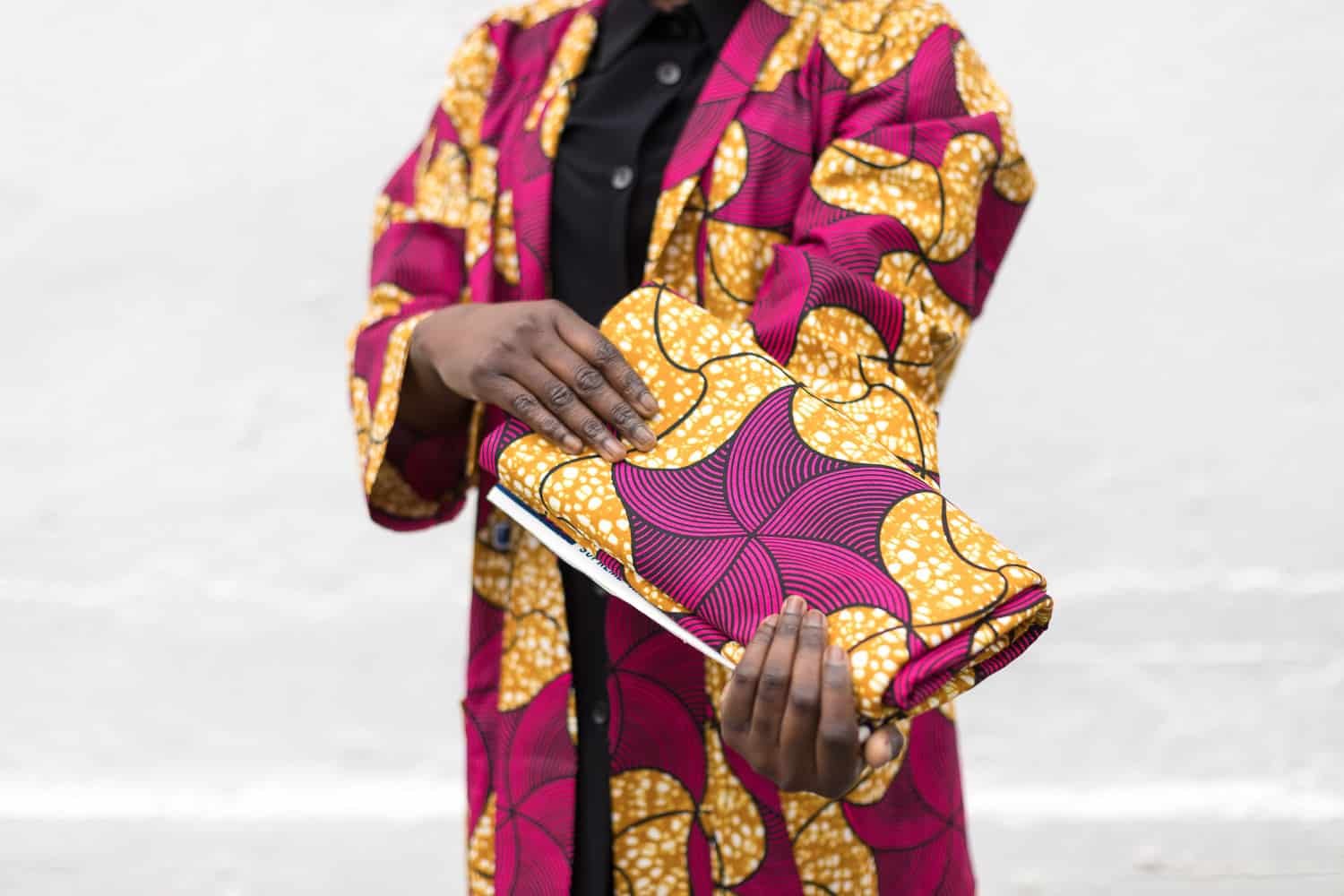 Retrato profesional de una modelo mostrando una tela africana rosa y amarilla