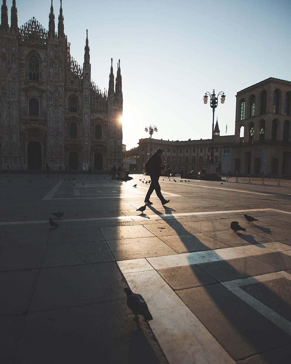 Persona paseando al amanecer en la Plaza del Duomo en Milán