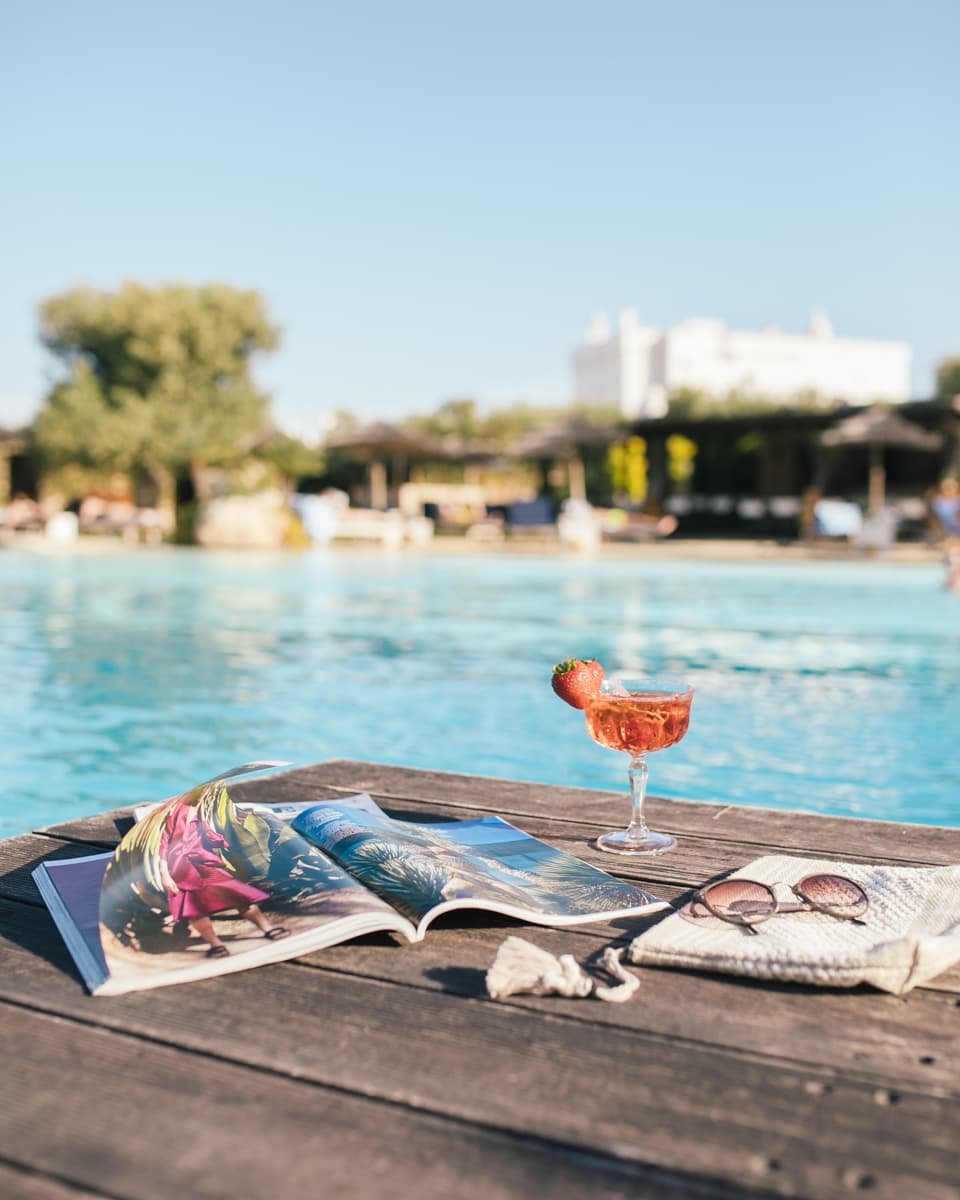 Revista gafas y bolso junto a una piscina