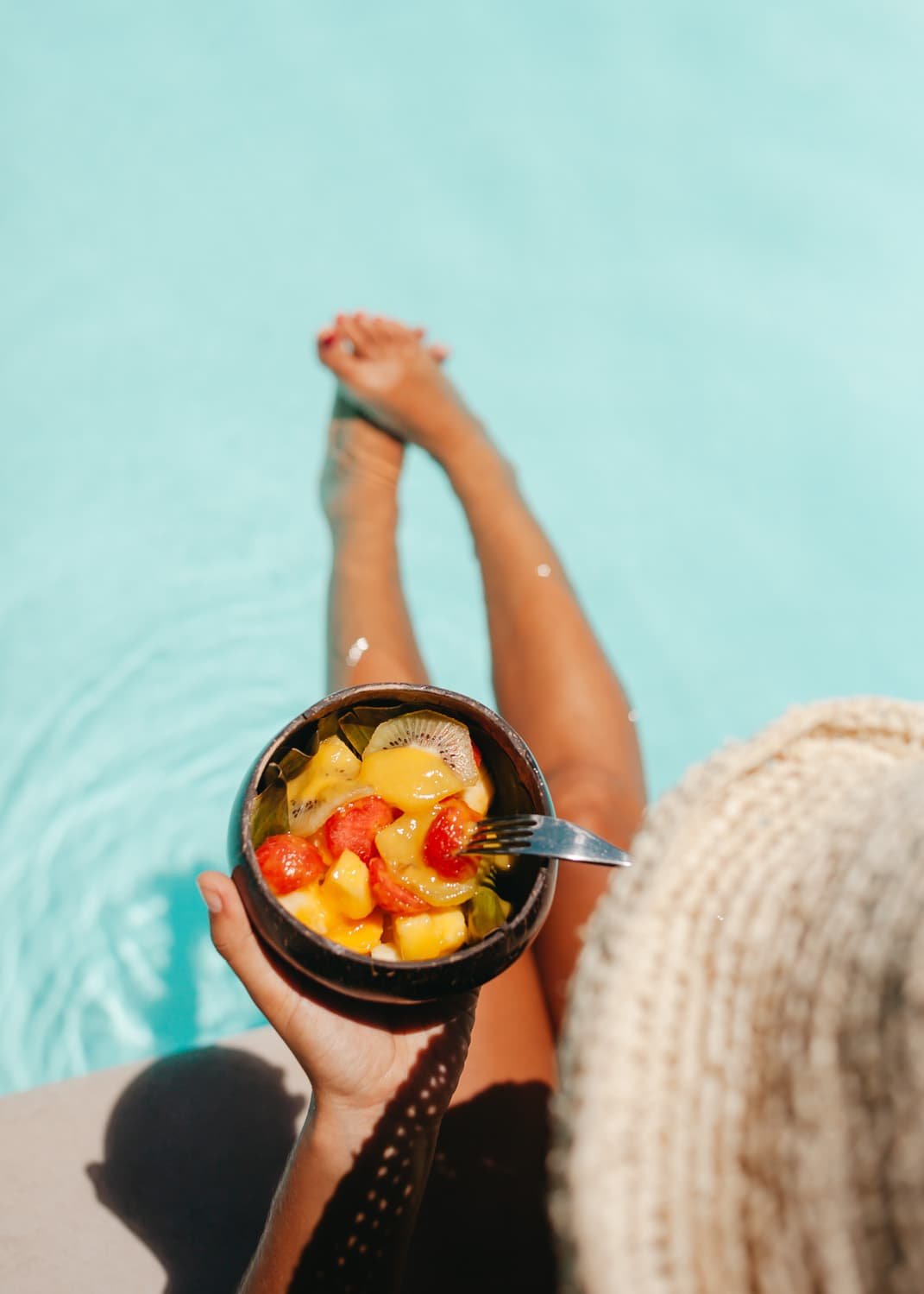 Fotografía profesional de una persona comiendo frutas en una piscina