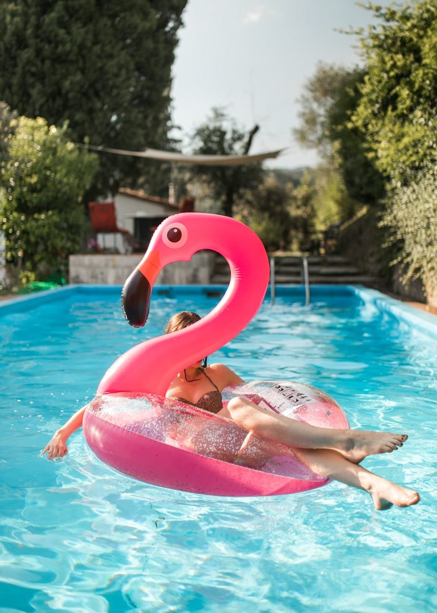 Fotografía profesional de una mujer en la pisicina de un hotel con un flotador con forma de flamenco